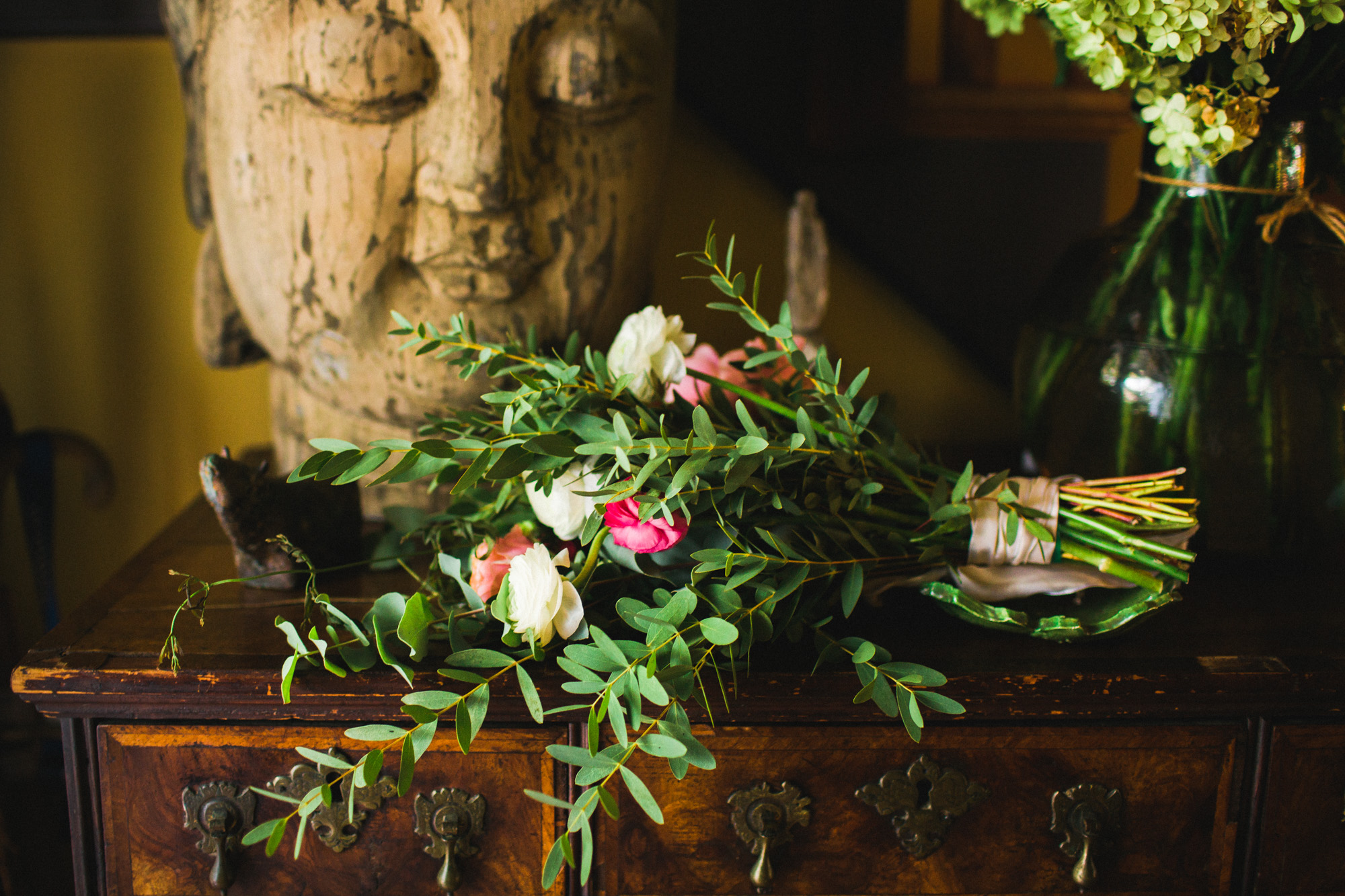 You might want to hire a professional wedding photographer reason 39: Artful photo of a bouquet resting by Buddha.