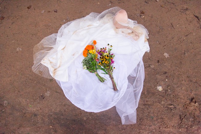 trashed wedding dress and bouquet in the mud