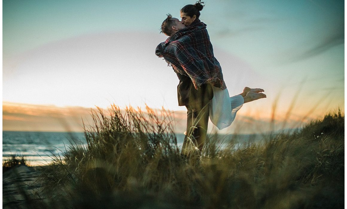 Ocean Beach San Francisco Engagement Photos man lifting woman in the sand dunes and kissing