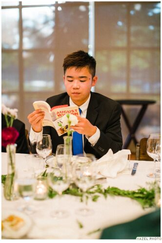 teenage boy reading book associated with tablescape decoration at wedding