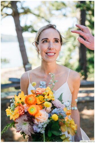 beautiful bride looks off camera as hand wipes a flyaway hair from face