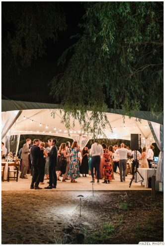 nighttime shot of guests under white tent