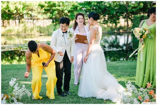 image of wedding couple laughing as bridesmaid drops ring during ceremony