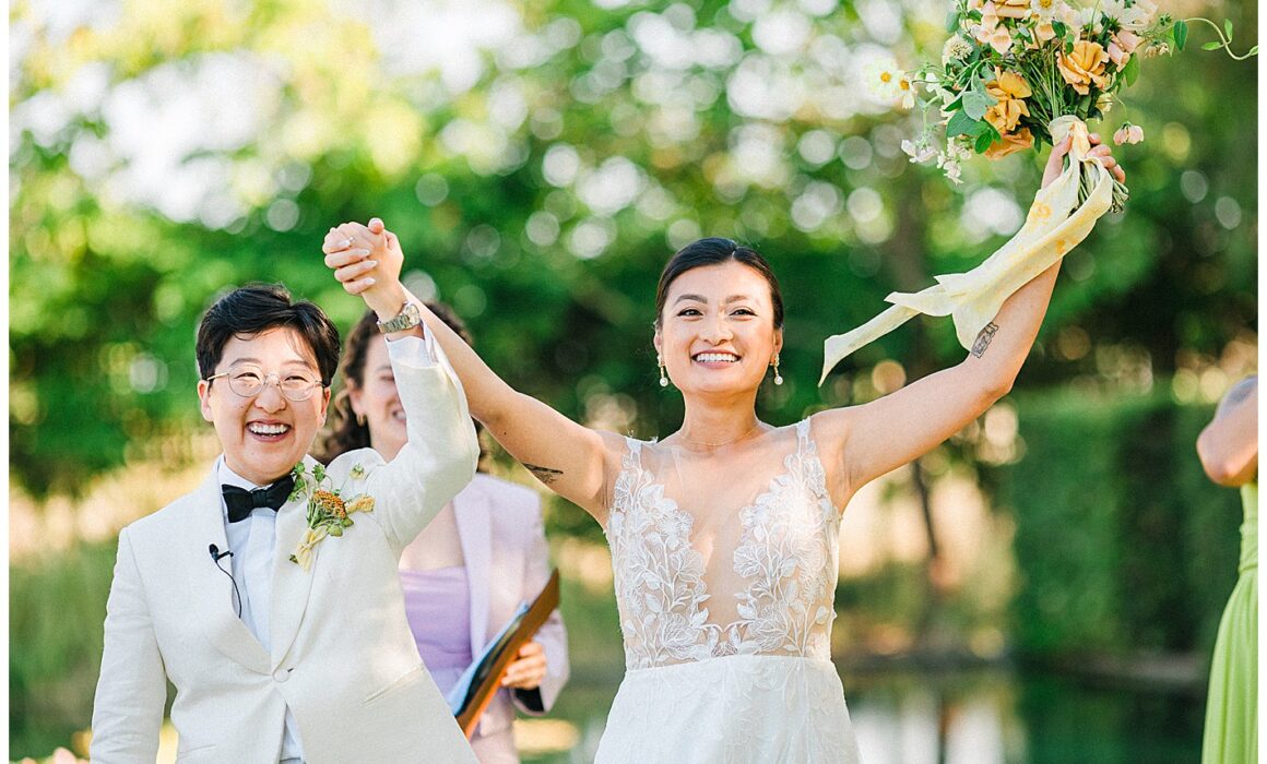 triumphant photo of newlyweds smiling, hands raised