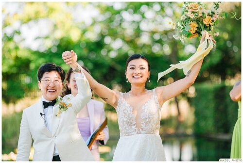 triumphant photo of newlyweds smiling, hands raised