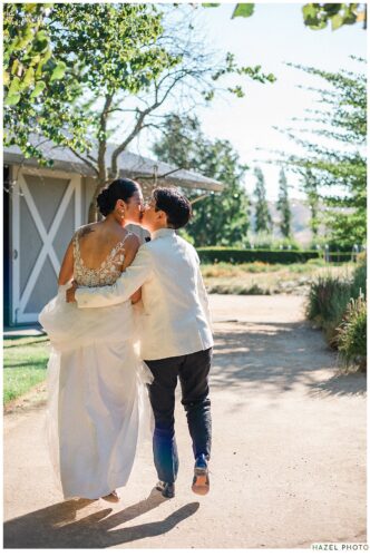 newlyweds with their backs turned away from the camera, walking away kissing.