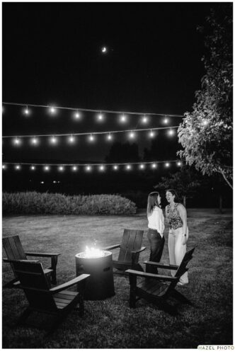 intimate photo of couple under string lights near fire pit