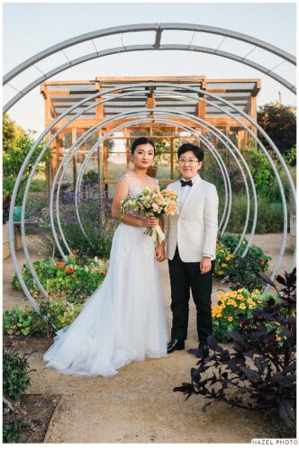 golden hour portrait of newlyweds at cornerstone garden among art sculpture