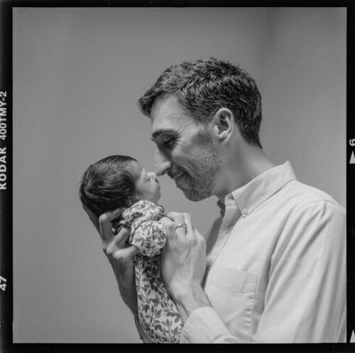 Black and white film photograph of a father and newborn in berkeley california